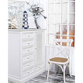 Tengerparti stílusú szobabelső fehér komóddal és fehér szilfa étkezőszékkel.